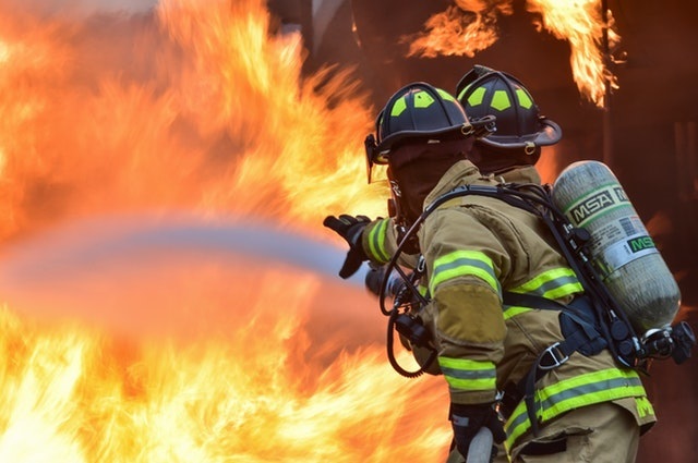 two firemen housing a big fire